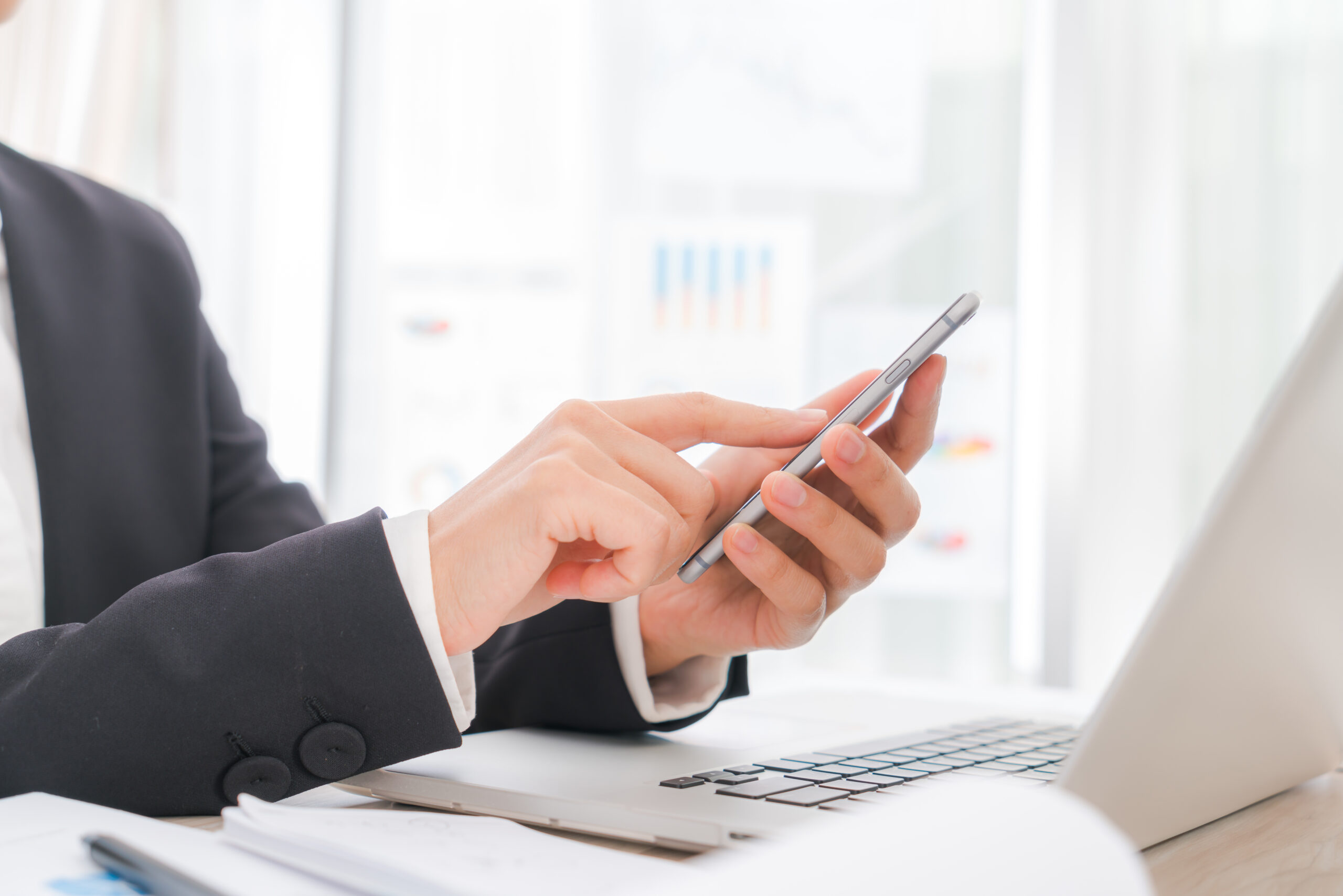 "Businesswoman using smartphone and laptop to contact clients"