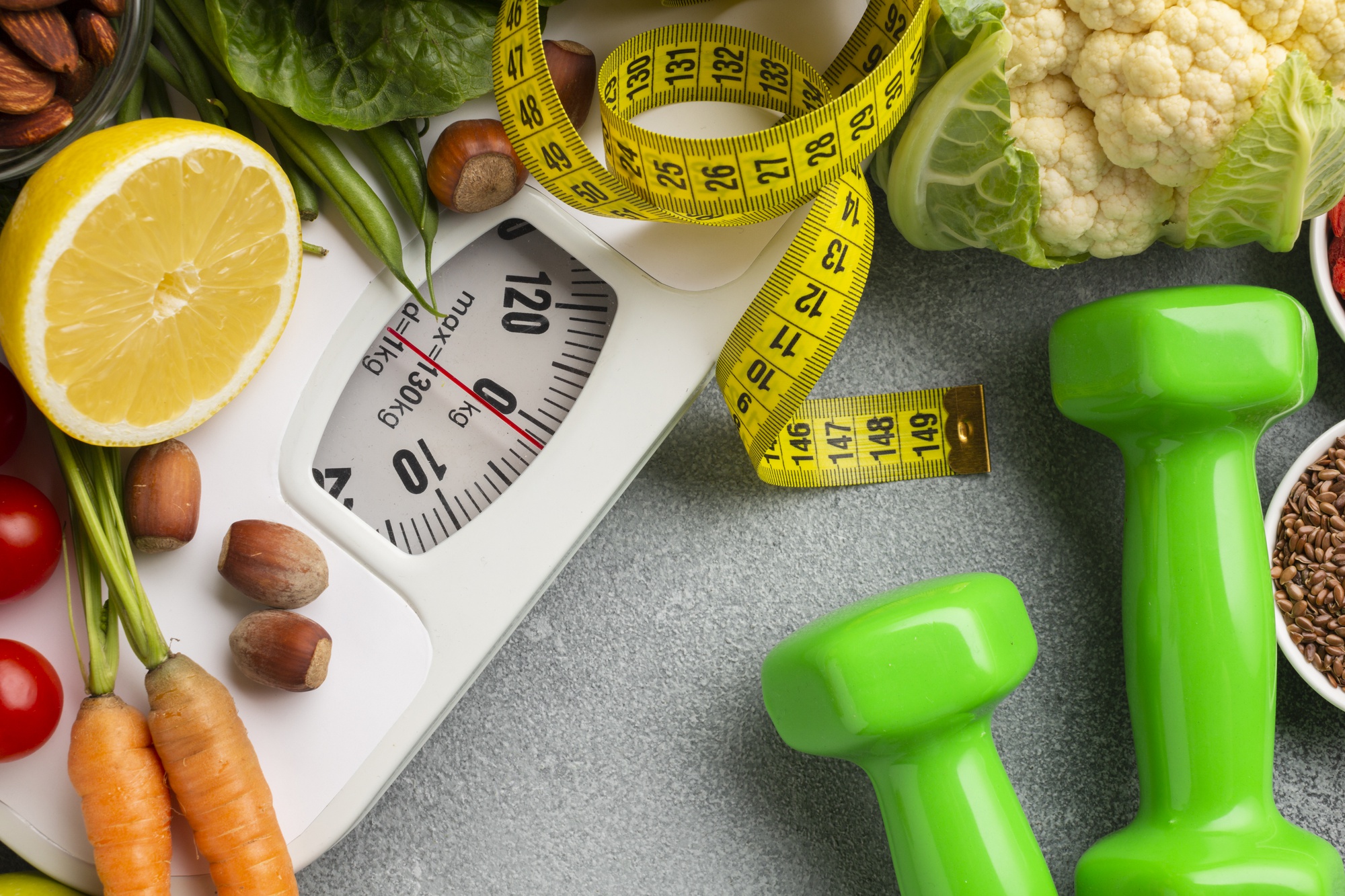 A flat lay composition of a digital bathroom scale and dumbbells on a neutral background, symbolizing tools for tracking fitness progress and weight management.