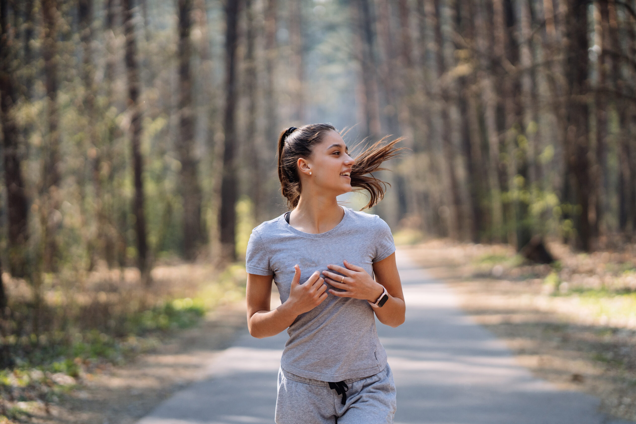 Woman running outdoors on a forest trail during a sunny morning exercise routine